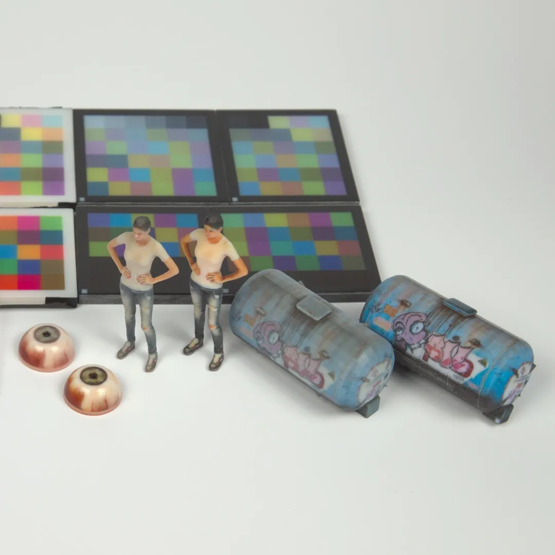 Exemplary full-color 3D printouts: A 3D printed human eye, a female figurine and model train container with a graffiti.
